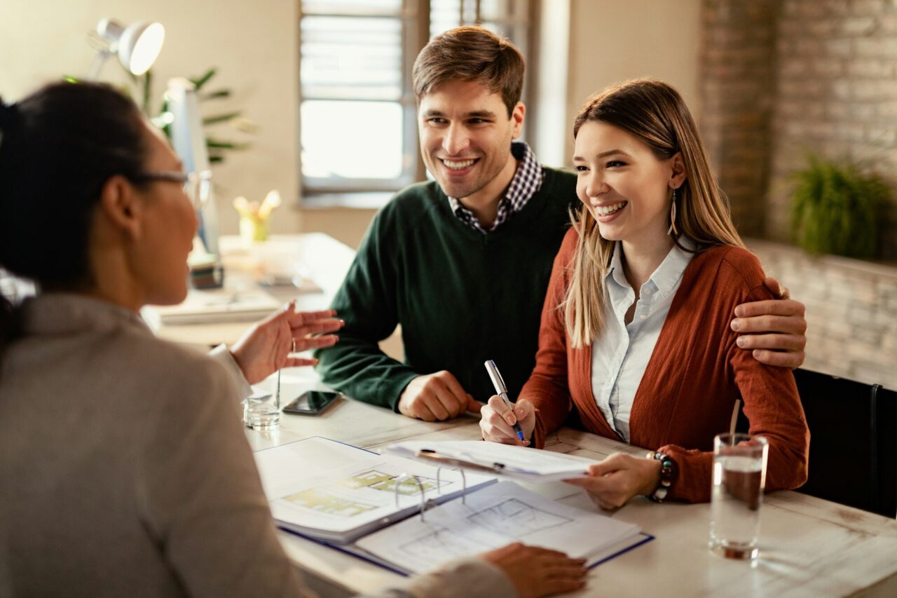 happy-couple-signing-mortgage-contract-while-having-meeting-with-real-estate-agent-.jpg